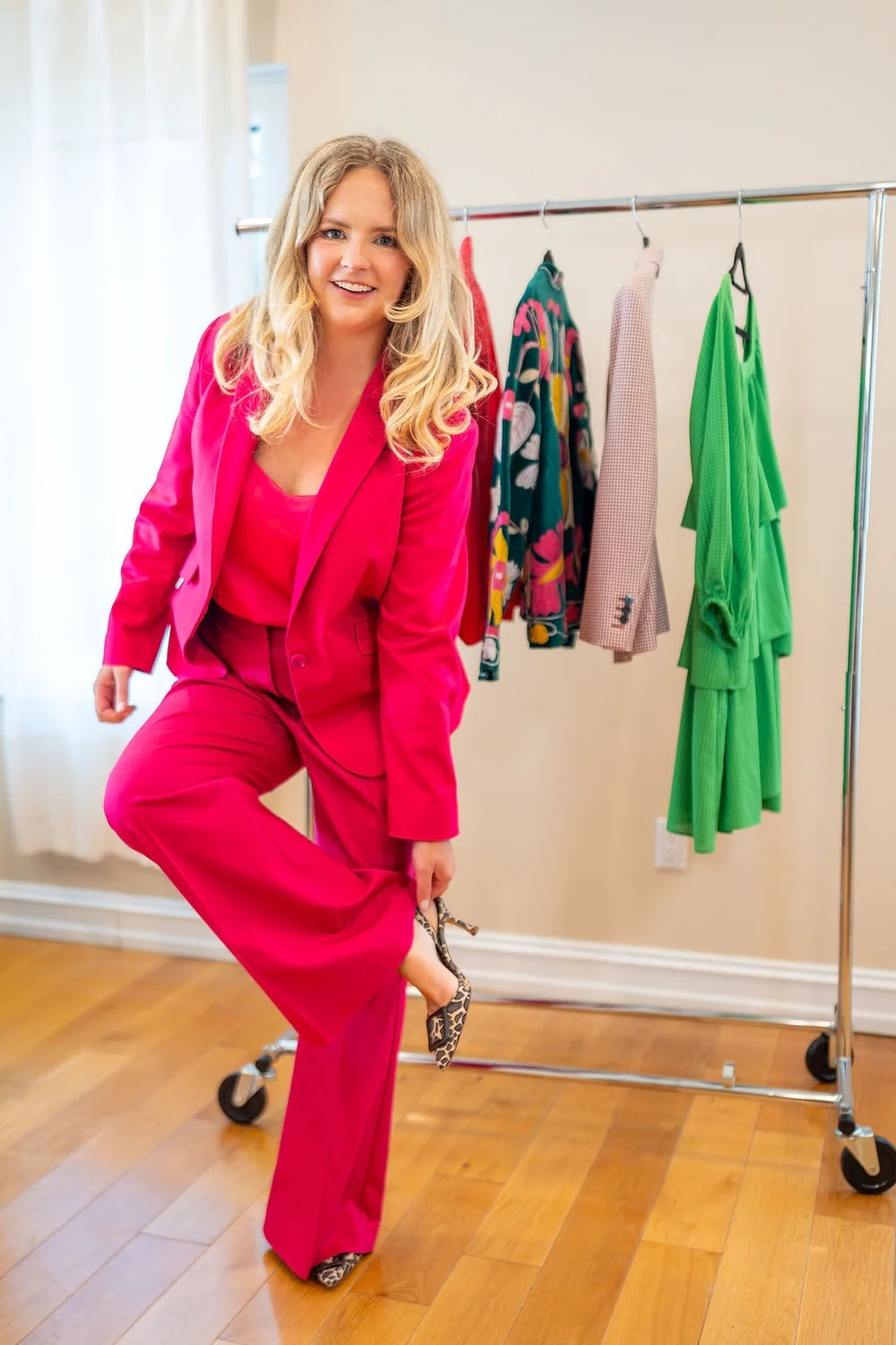 Monika wearing a bright pink business-casual power suit with patterned heels